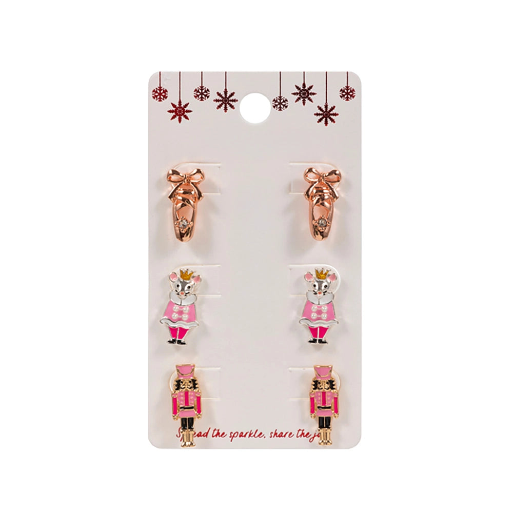 The image features a Nutcracker Trio Earring Set by an unspecified brand, displayed on a card. The set includes three pairs of holiday-themed stud earrings: a pair of ballet slippers in rose gold, a pair depicting a pink-dressed.