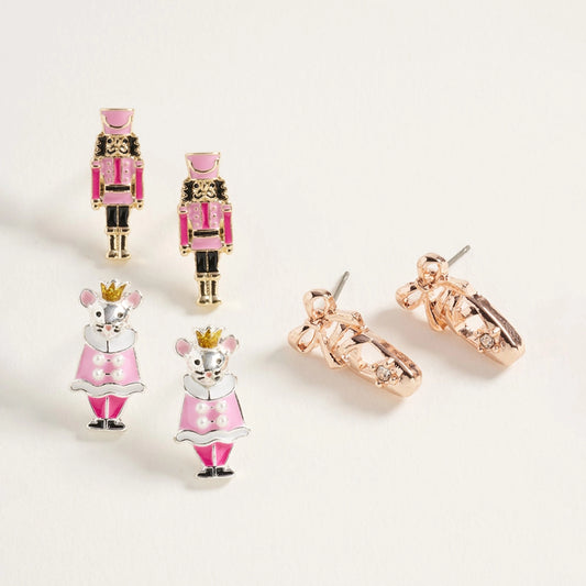 A festive Nutcracker Trio Earring Set features three pairs of stud earrings: two nutcracker soldier designs in pink and gold, a pair of ballet-inspired mouse earrings in pink and white with crowns, and a rose gold pair adorned.