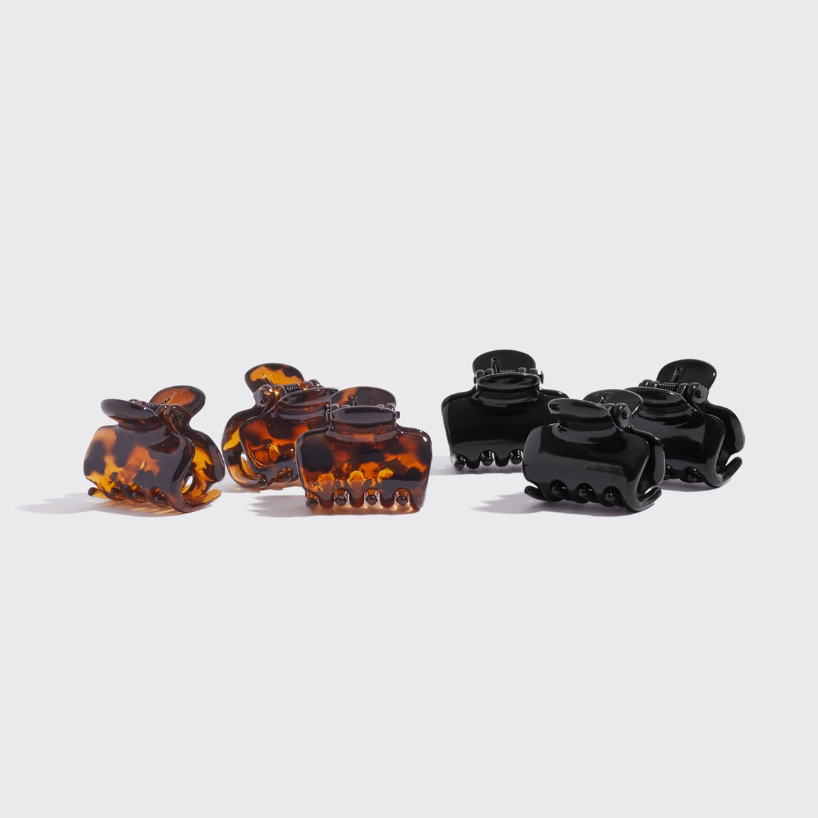 A set of six mini claw clips featuring three black and three tortoise designs. The clips have a glossy finish and a cloud-like shape, ideal for securely holding various hair types while adding a stylish touch to hairstyles.
