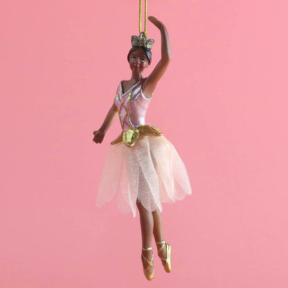 A graceful rose gold ballerina ornament stands poised on pointe, wearing a delicate fabric tutu adorned with shimmer.