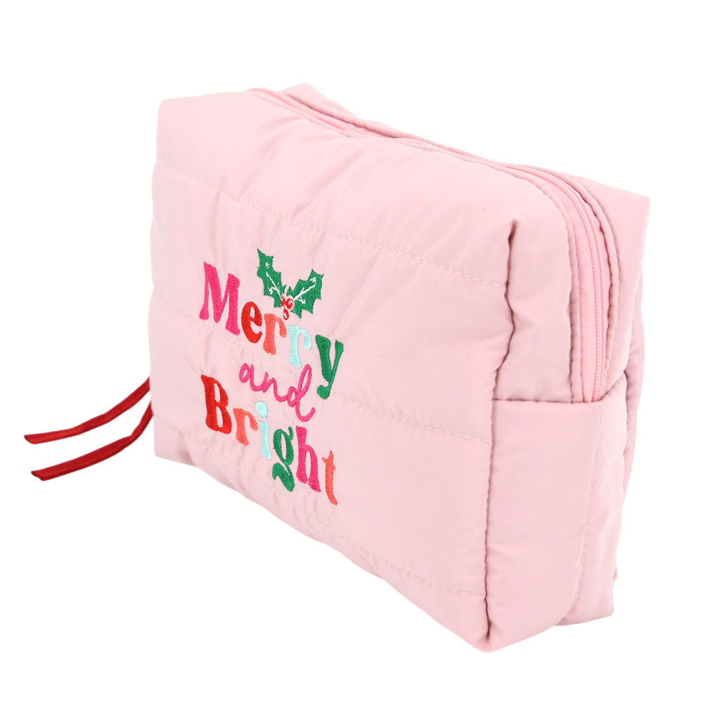 A pink quilted cosmetic pouch bag features festive embroidered lettering that reads Merry and Bright, adorned with green holly leaves.