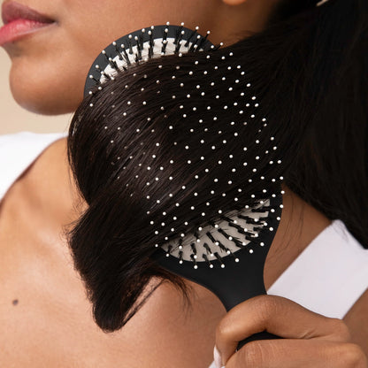 A close-up image features a hand holding a Smooth & Polish Brush with a dual-bristle design, showcasing its black handle and cushioned rubber pad.