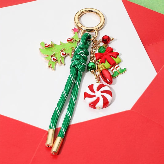 A festive keychain features a playful design with a green Christmas tree, a red and white peppermint candy, and a cheerful ornament-inspired figure.