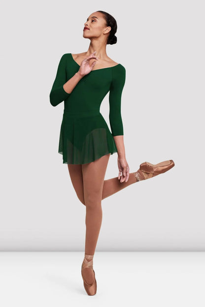 A model gracefully poses in a green long-sleeve leotard paired with a short mesh skirt, showcasing the Ladies Jaye Mesh Skirt (R4211) by the brand.