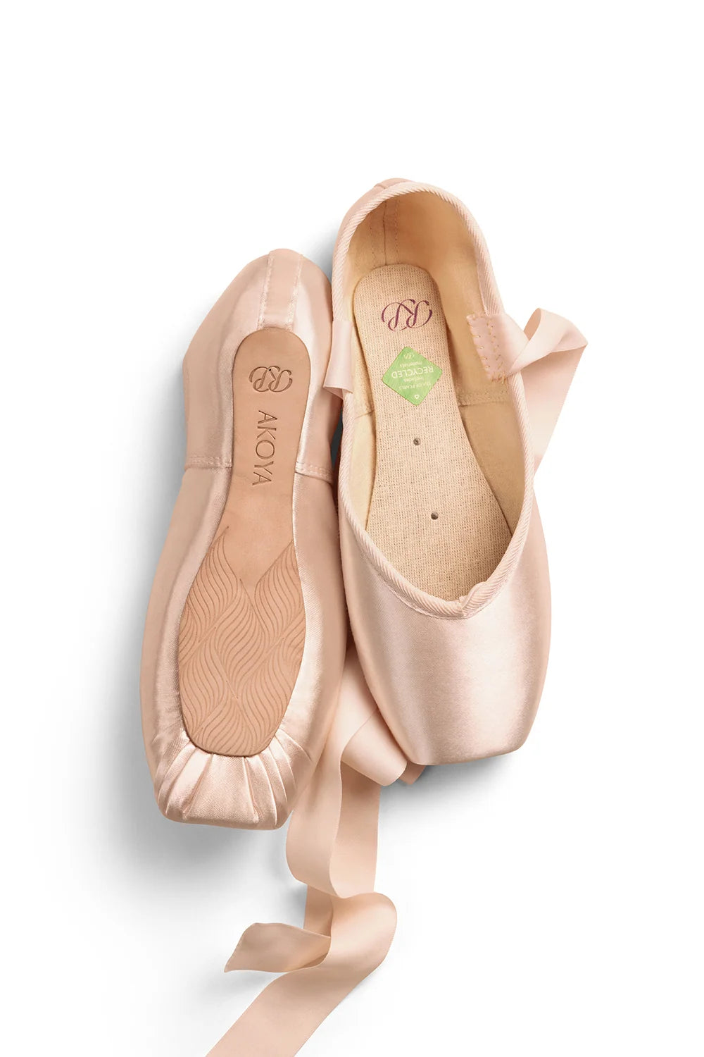 The image features a pair of Akoya pointe shoes in a soft, light pink color. The shoes are displayed side by side, showcasing their sleek satin finish, tapered box, and flexible shank design, with visible ribbons attached.