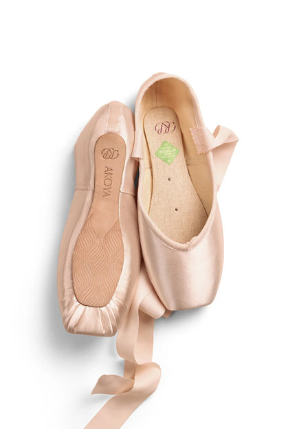 The image features a pair of Akoya pointe shoes in a soft, light pink color. The shoes are displayed side by side, showcasing their sleek satin finish, tapered box, and flexible shank design, with visible ribbons attached.