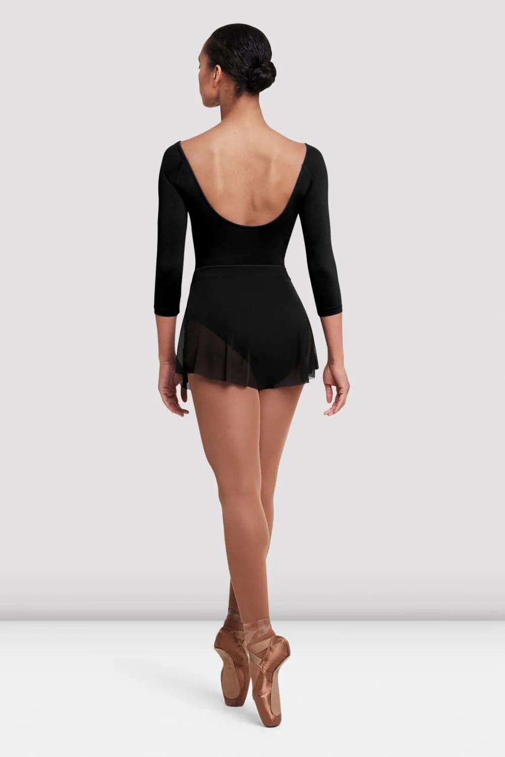 A model is seen from the back wearing a black Ladies Jaye Mesh Skirt by the brand, styled with a fitted leotard.