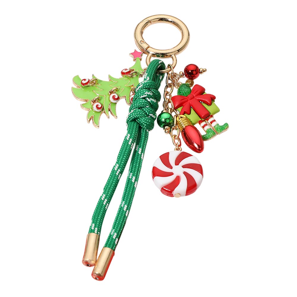 A festive keychain featuring a green decorative cord with two tassels, attached to a gold ring. The charm design includes a playful Christmas tree, a wrapped gift, peppermint candy, and ornament-inspired accents in vibrant red.