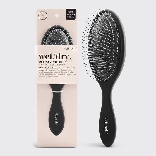 The Kitsch Wet/Dry Brush in sleek black features thin, flexible bristles designed for gentle detangling, displayed alongside its packaging.