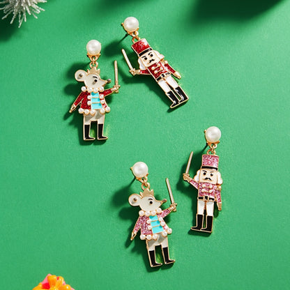 A pair of whimsical enamel nutcracker dangle earrings features a mouse and a nutcracker soldier, each adorned with colorful detailing.