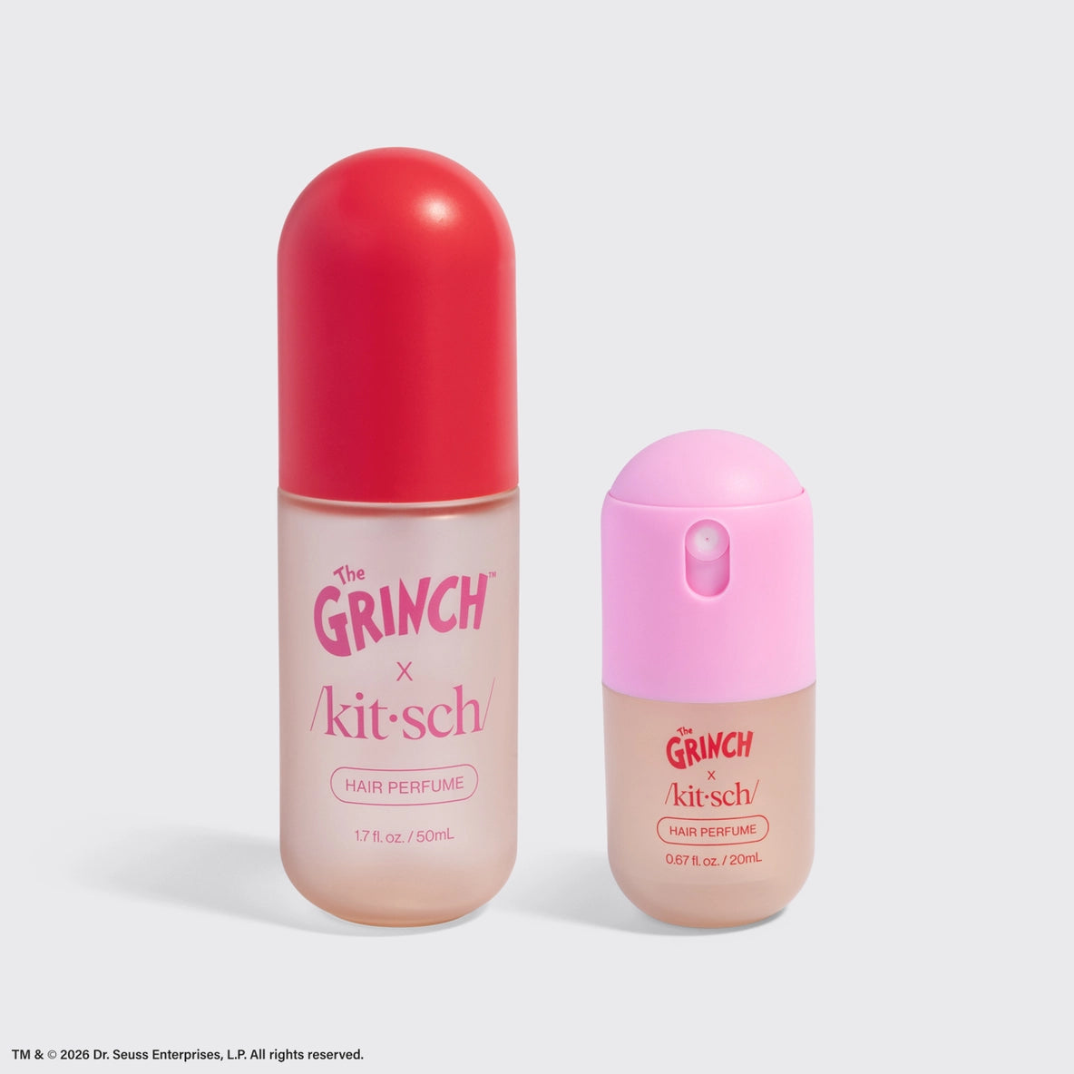 The image features two hair perfume bottles from The Grinch x Kitsch collaboration. On the left is a larger bottle with a clear body and a red cap, while the smaller bottle on the right has a pink cap.