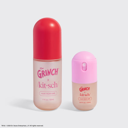 The image features two hair perfume bottles from The Grinch x Kitsch collaboration. On the left is a larger bottle with a clear body and a red cap, while the smaller bottle on the right has a pink cap.