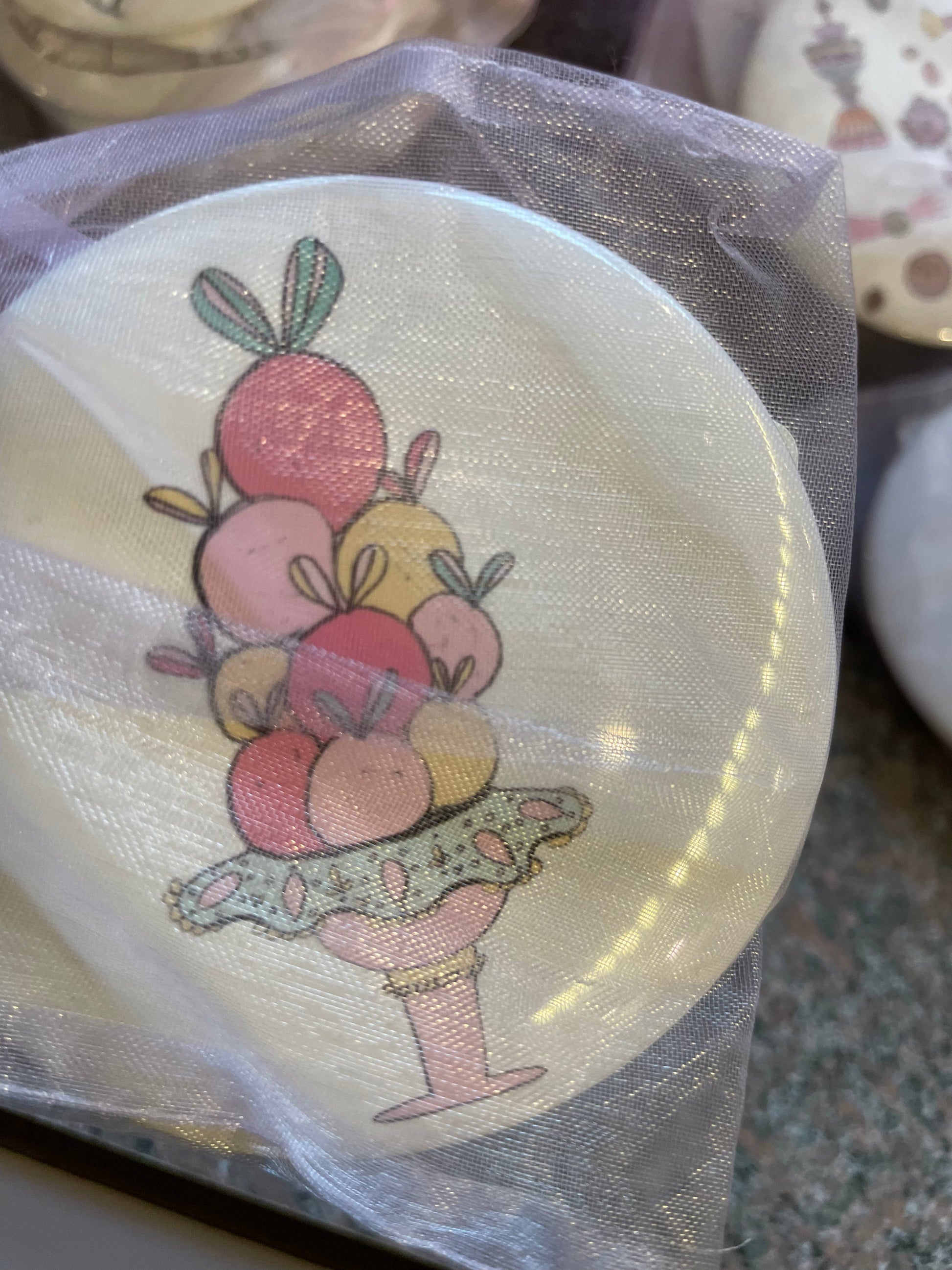 A Nutcracker-themed pocket mirror featuring a vibrant illustration of a decorative dessert display, adorned with colorful macaroons and fruits.