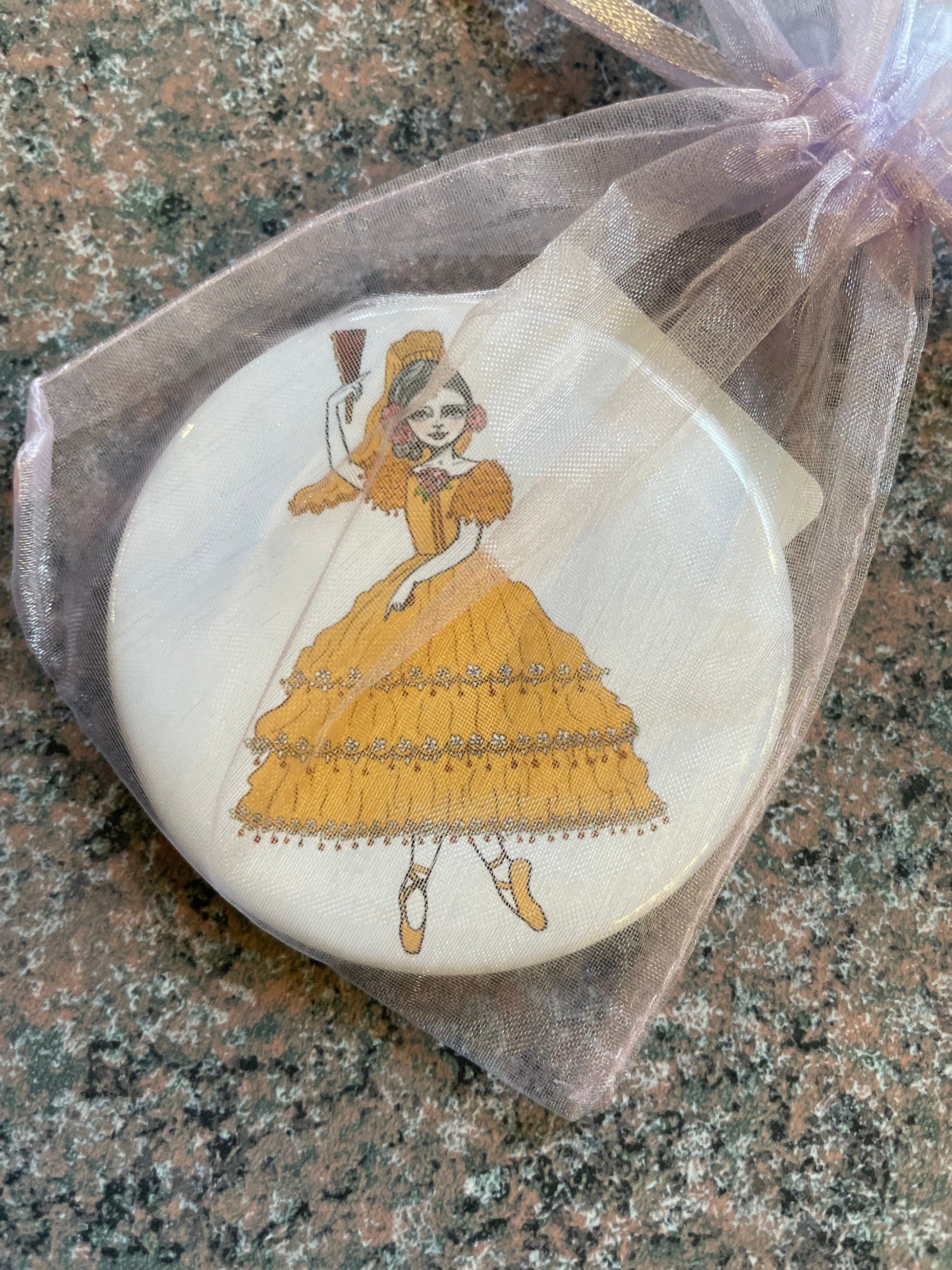 A Nutcracker-themed pocket mirror featuring a whimsical illustration of a ballerina in a yellow dress, elegantly holding a fan.